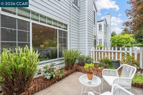 a view of a chair and table in the patio in front of a house