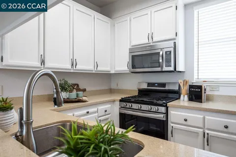 a kitchen with stainless steel appliances a stove a sink a microwave and cabinets