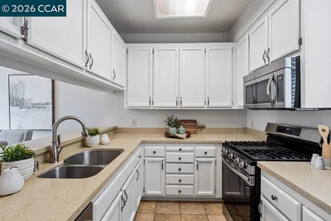 a kitchen with white cabinets a sink stove and microwave