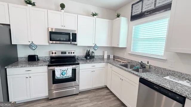a kitchen with stainless steel appliances granite countertop white cabinets granite counter tops and a window