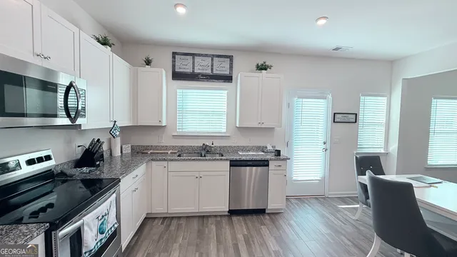 a kitchen with stainless steel appliances granite countertop a stove a sink dishwasher a microwave oven and a refrigerator with wooden floor