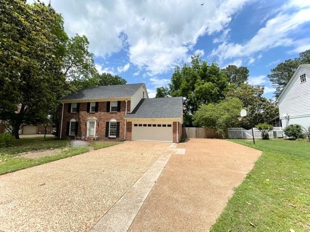front view of house with a yard and trees