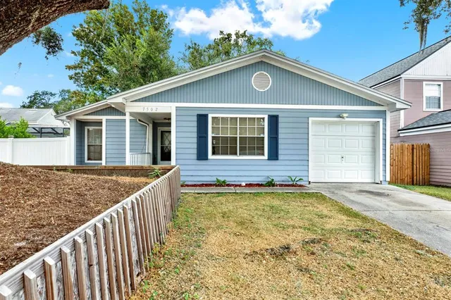 a front view of house with yard and trees in the background