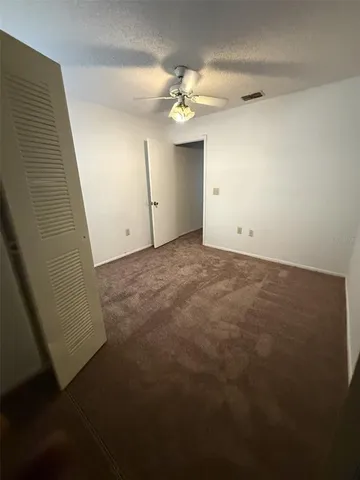 an empty room with a chandelier fan and closet