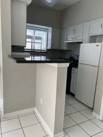 a kitchen with a refrigerator a stove a microwave and a window