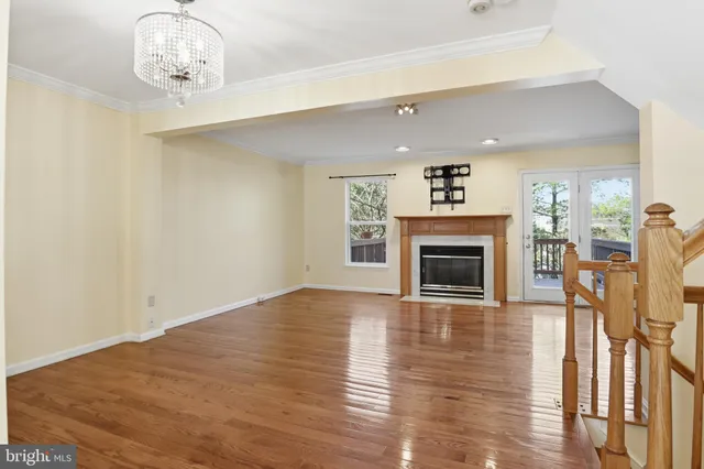 a view of a livingroom with a fireplace a chandelier wooden floor and windows