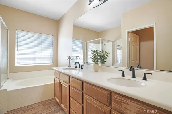 a bathroom with a sink double vanity granite tub shower and a mirror