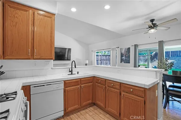 a kitchen with a sink dishwasher a stove and white cabinets with wooden floor