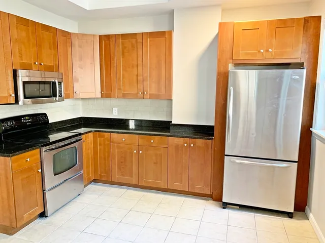 a kitchen with granite countertop a refrigerator a stove a sink and dishwasher