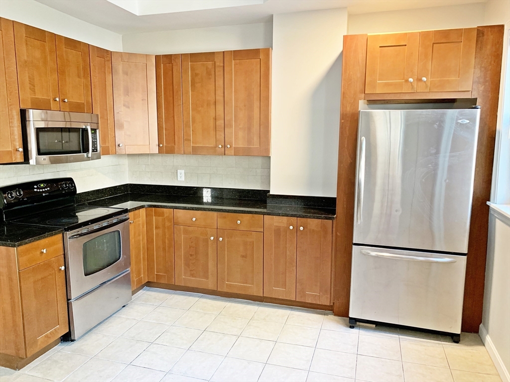 a kitchen with granite countertop a refrigerator a stove a sink and dishwasher