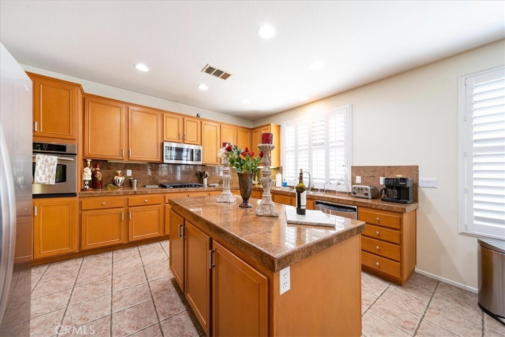 13449 Quail Run Road Eastvale, CA 92880 - Photo 26 of 59 a kitchen with stainless steel appliances granite countertop a sink counter space cabinets and a large window