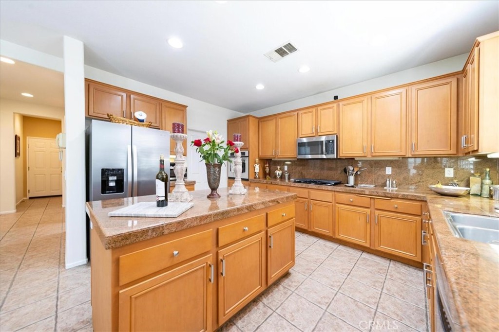 13449 Quail Run Road Eastvale, CA 92880 - Photo 27 of 59 a kitchen with stainless steel appliances granite countertop a stove sink and cabinets