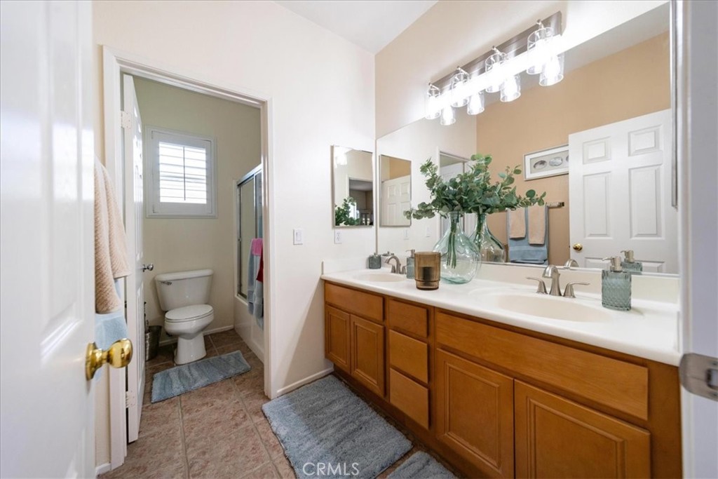 13449 Quail Run Road Eastvale, CA 92880 - Photo 44 of 59 a spacious bathroom with a double vanity sink toilet and a mirror