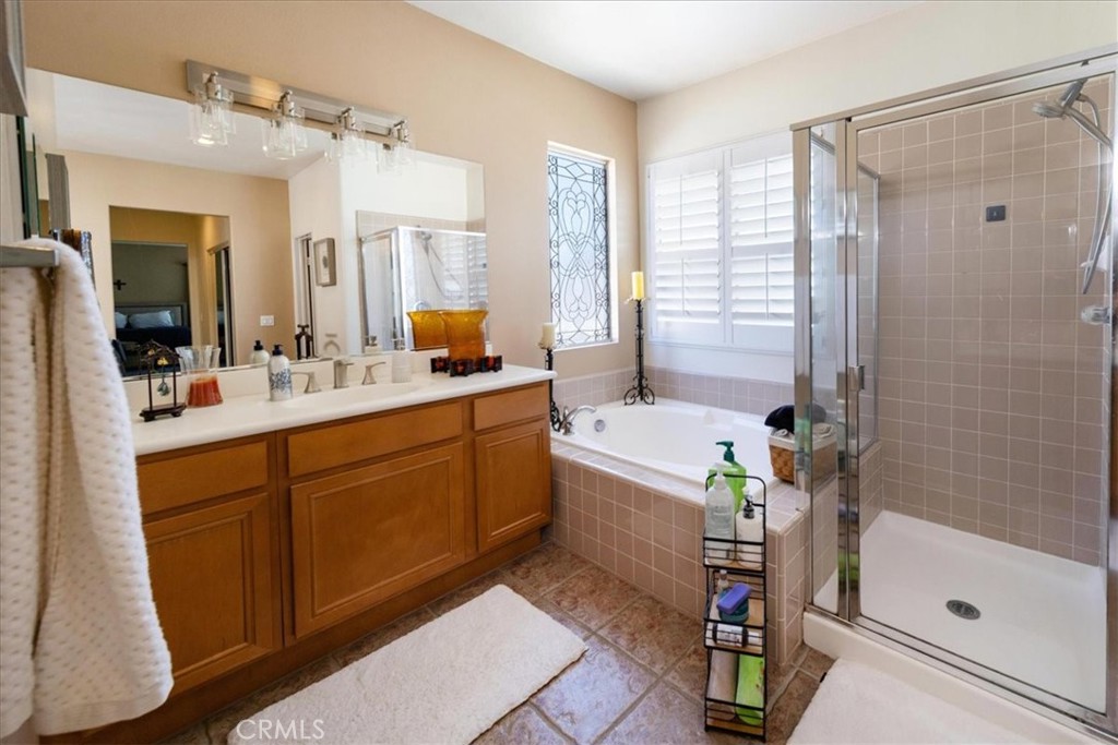 13449 Quail Run Road Eastvale, CA 92880 - Photo 51 of 59 a bathroom with a tub a sink shower and mirror