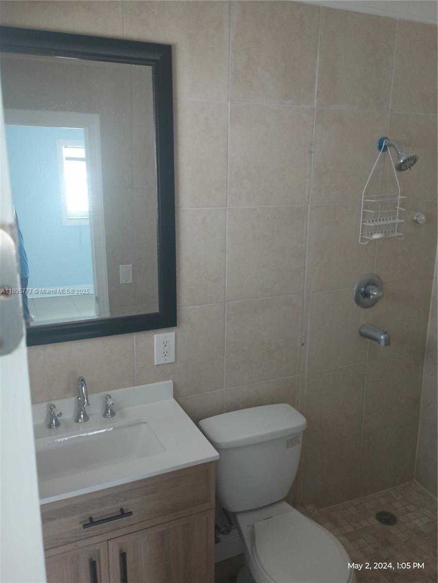 258 Neptune Avenue, Unit N Lauderdale-by-the-Sea, FL 33308 - Photo 12 of 14 a bathroom with a granite countertop sink toilet and a mirror
