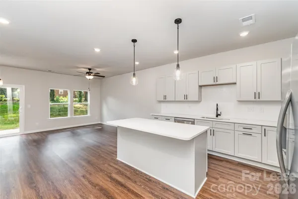 a kitchen with stainless steel appliances granite countertop a sink a stove a refrigerator and white cabinets with wooden floor