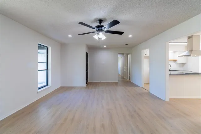 a view of an empty room with window and wooden floor