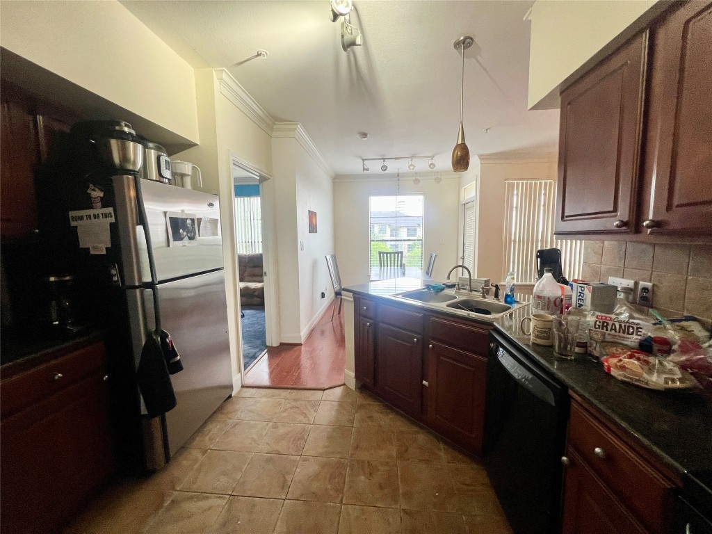 7701 Rialto Boulevard, Unit 1328 Austin, TX 78735 - Photo 8 of 17 Kitchen featuring a peninsula, ornamental molding, black dishwasher, freestanding refrigerator, and hanging light fixtures