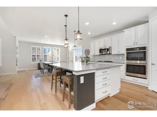 a kitchen with kitchen island granite countertop a stove a sink a dining table and chairs with wooden floor