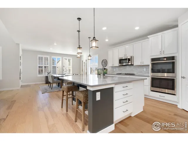 a kitchen with kitchen island granite countertop a stove a sink a dining table and chairs with wooden floor