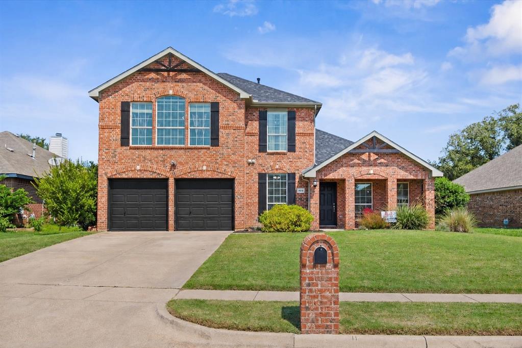 409 Springtree Road Lake Dallas, TX 75065 - Photo 2 of 40 Brick facade, arched garage door openings, two-car garage, covered entry, and gabled roofline