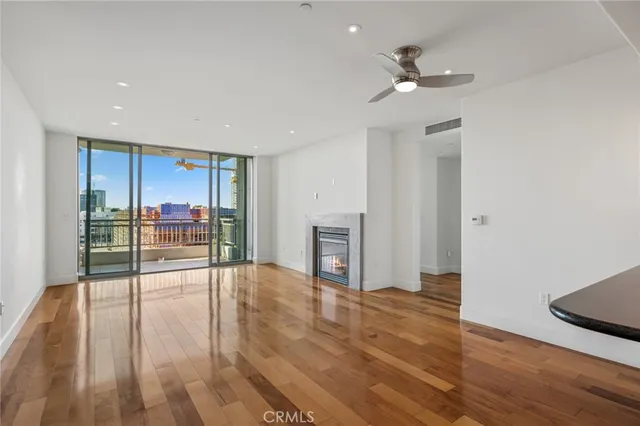 a view of an empty room with wooden floor and a kitchen