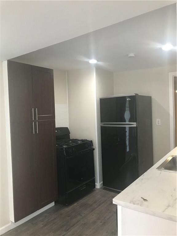 1119 Spur Street, Unit A Austin, TX 78721 - Photo 10 of 10 A compact kitchen with sleek black appliances and modern gray flooring.