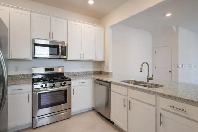 a kitchen with granite countertop white cabinets and stainless steel appliances