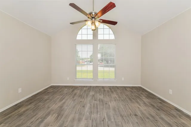 an empty room with wooden floor and windows