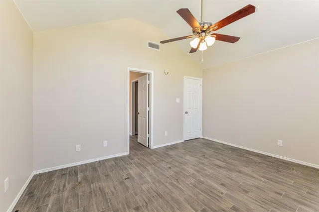 an empty room with wooden floor and ceiling fan
