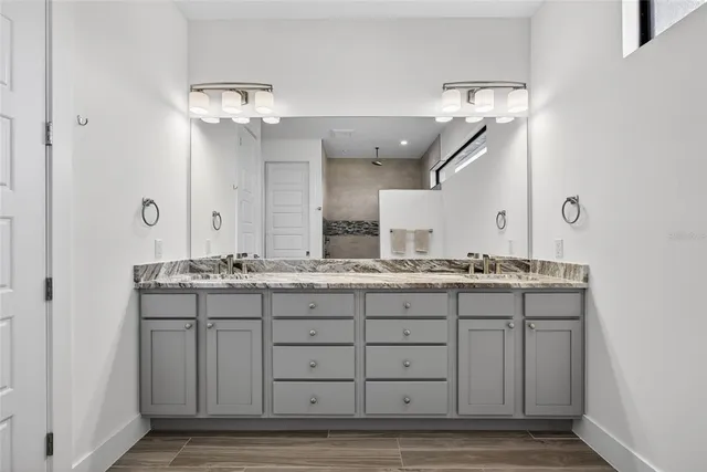 a bathroom with a granite countertop sink two mirror and a vanity