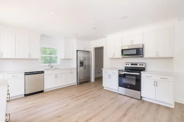 a kitchen with granite countertop a refrigerator stove and sink