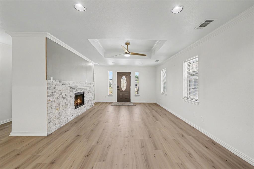 307 Dixon Street Terrell, TX 75160 - Photo 5 of 32 Spacious living area featuring wood-finish flooring, a stone-clad fireplace, recessed lighting, and a tray ceiling with a ceiling fan