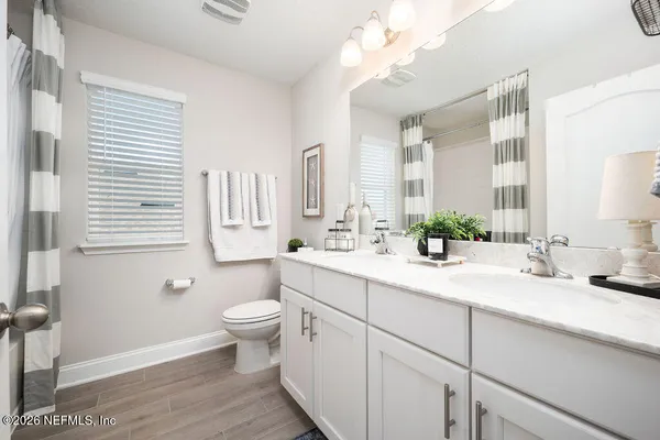 a bathroom with a double vanity sink toilet and a mirror