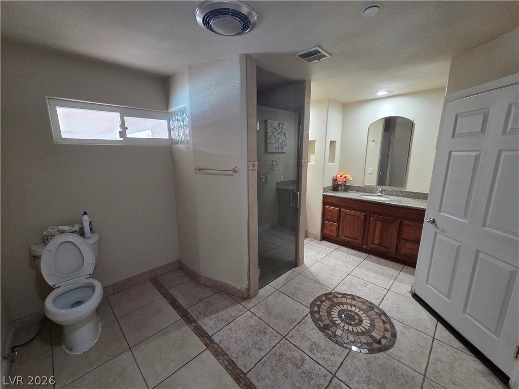 3381 Westwind Road Las Vegas, NV 89146 - Photo 41 of 52 A spacious bathroom features tile flooring, a large vanity, and a glass-enclosed shower.