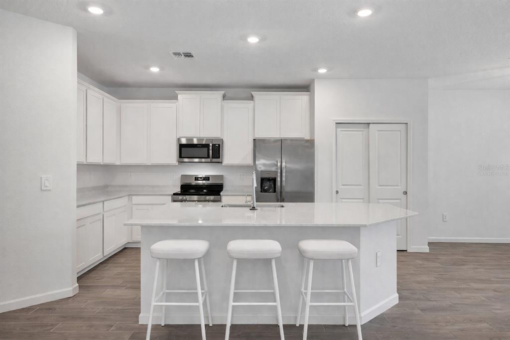 19426 Southwest 79th Street Dunnellon, FL 34432 - Photo 6 of 34 a kitchen with stainless steel appliances cabinets a sink and chairs