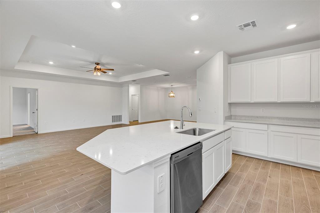 19426 Southwest 79th Street Dunnellon, FL 34432 - Photo 9 of 34 a kitchen with a sink dishwasher and white cabinets with wooden floor