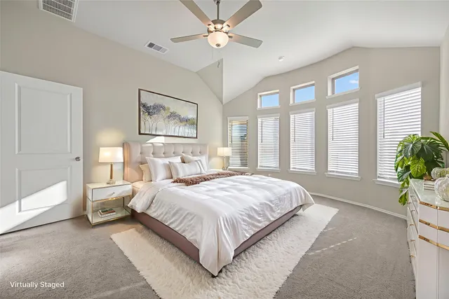 a bedroom with a large bed and a chandelier fan