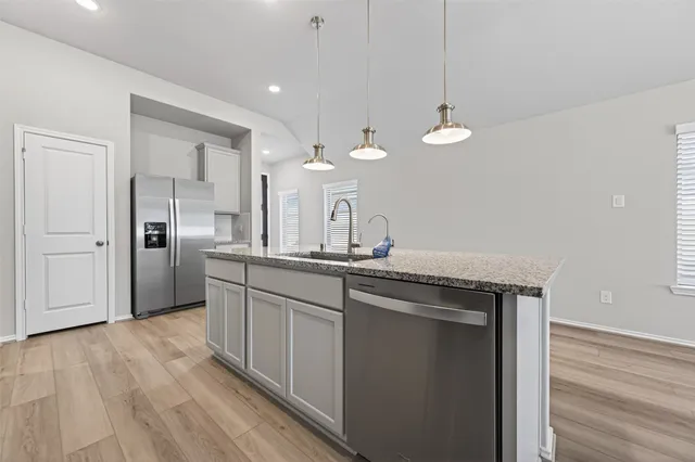 a kitchen with stainless steel appliances granite countertop a sink a refrigerator and a stove