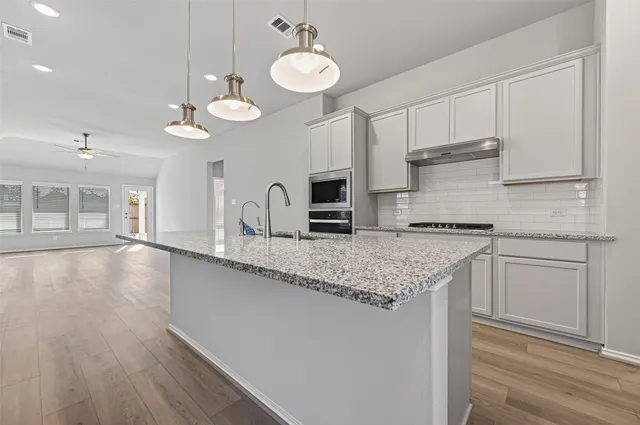 a kitchen with stainless steel appliances granite countertop a sink a stove and a wooden floors