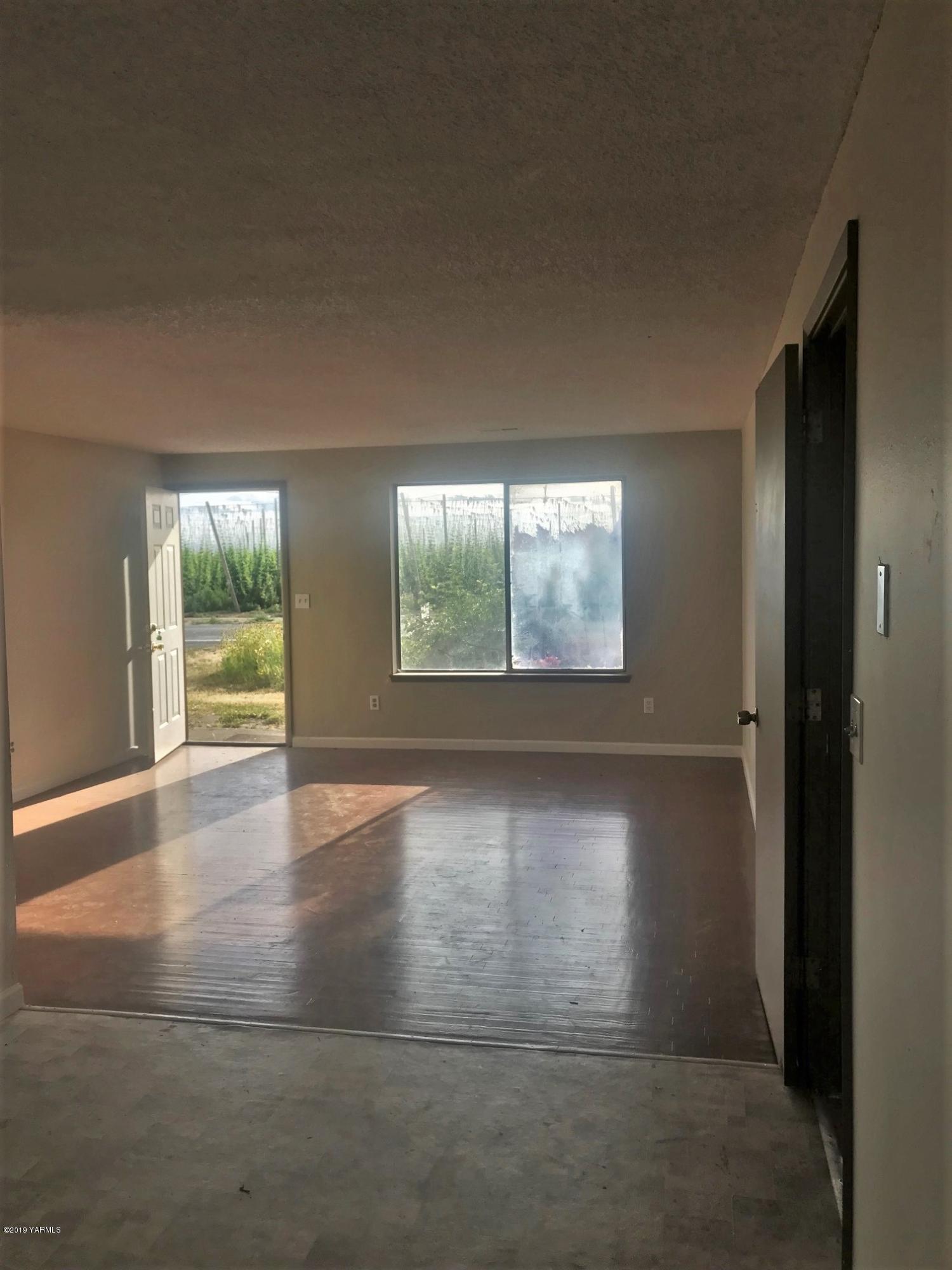 811 North County Line Road Grandview, WA 98930 - Photo 2 of 11 an empty room with wooden floor and windows