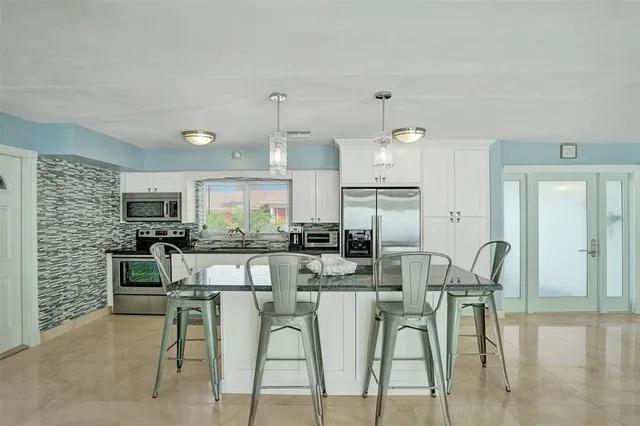 a kitchen with stainless steel appliances kitchen island granite countertop a dining table chairs and granite counter tops