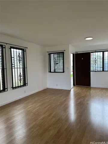 a view of an empty room with wooden floor and a window