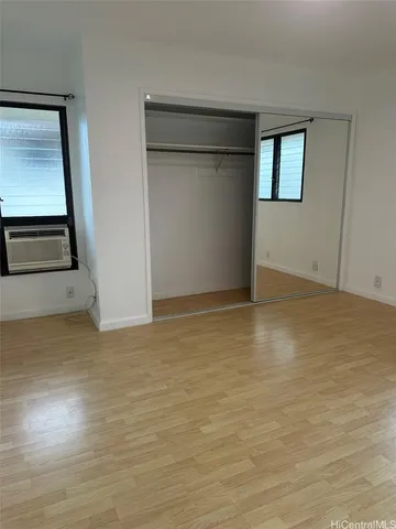 a view of an empty room with wooden floor and closet