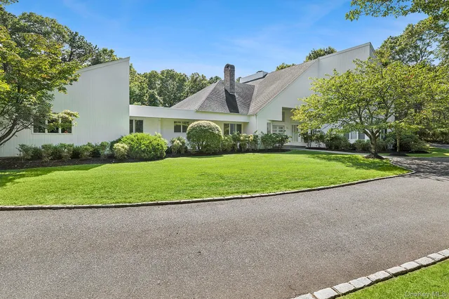 a view of a house with a big yard and large trees