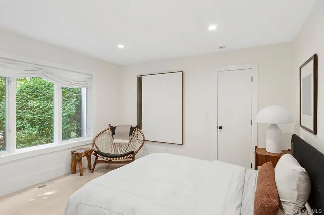 a bedroom with a bed and chair with the view of balcony