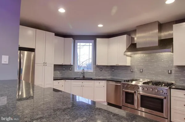 a kitchen with stainless steel appliances granite countertop a sink a stove and a refrigerator