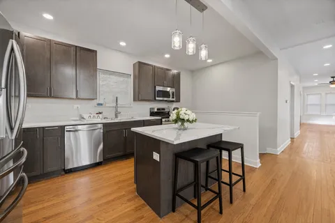 a kitchen with a sink stainless steel appliances and wooden floor