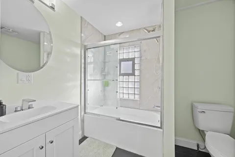 a bathroom with a granite countertop sink a toilet and shower