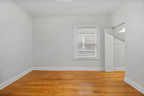 a view of an empty room with window and wooden floor